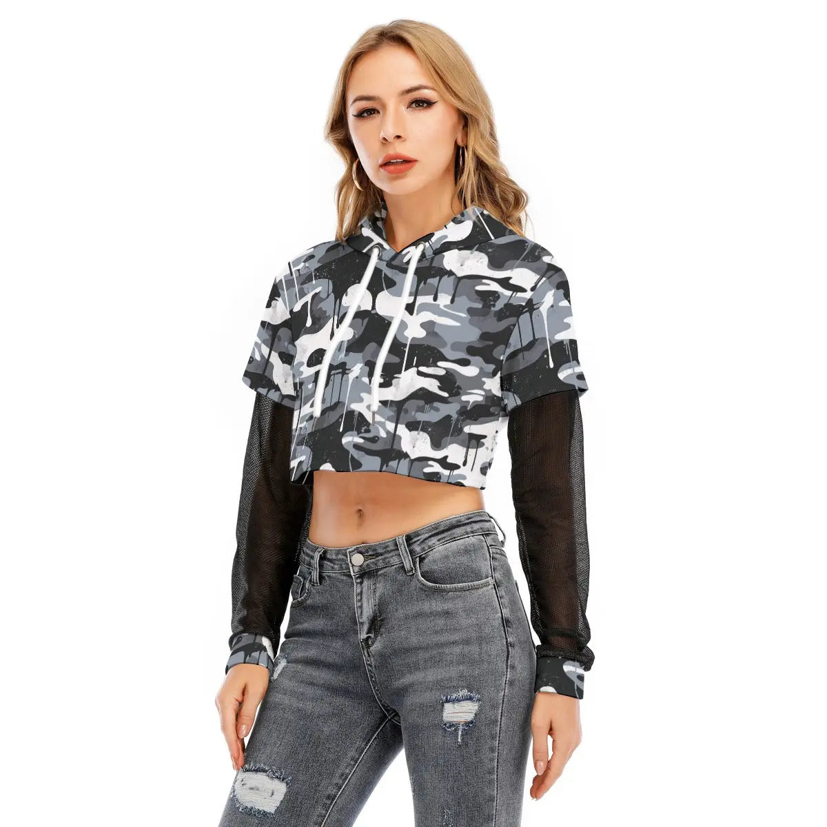 Woman wearing a layered crop top with mesh sleeves and camo print, styled with grey ripped jeans, showcasing sporty casual fashion.