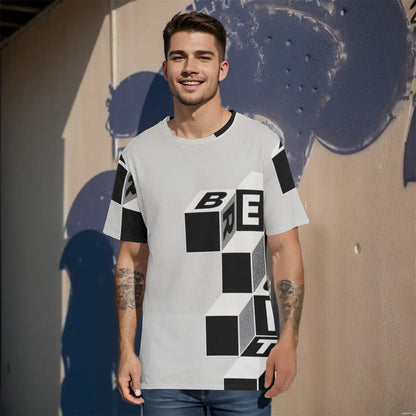 Young man wearing graphic cotton T-shirt with geometric cube design, standing against a textured wall in casual sunlight.