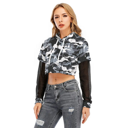 Woman wearing a layered crop top with mesh sleeves and camo print, styled with grey ripped jeans, showcasing sporty casual fashion.